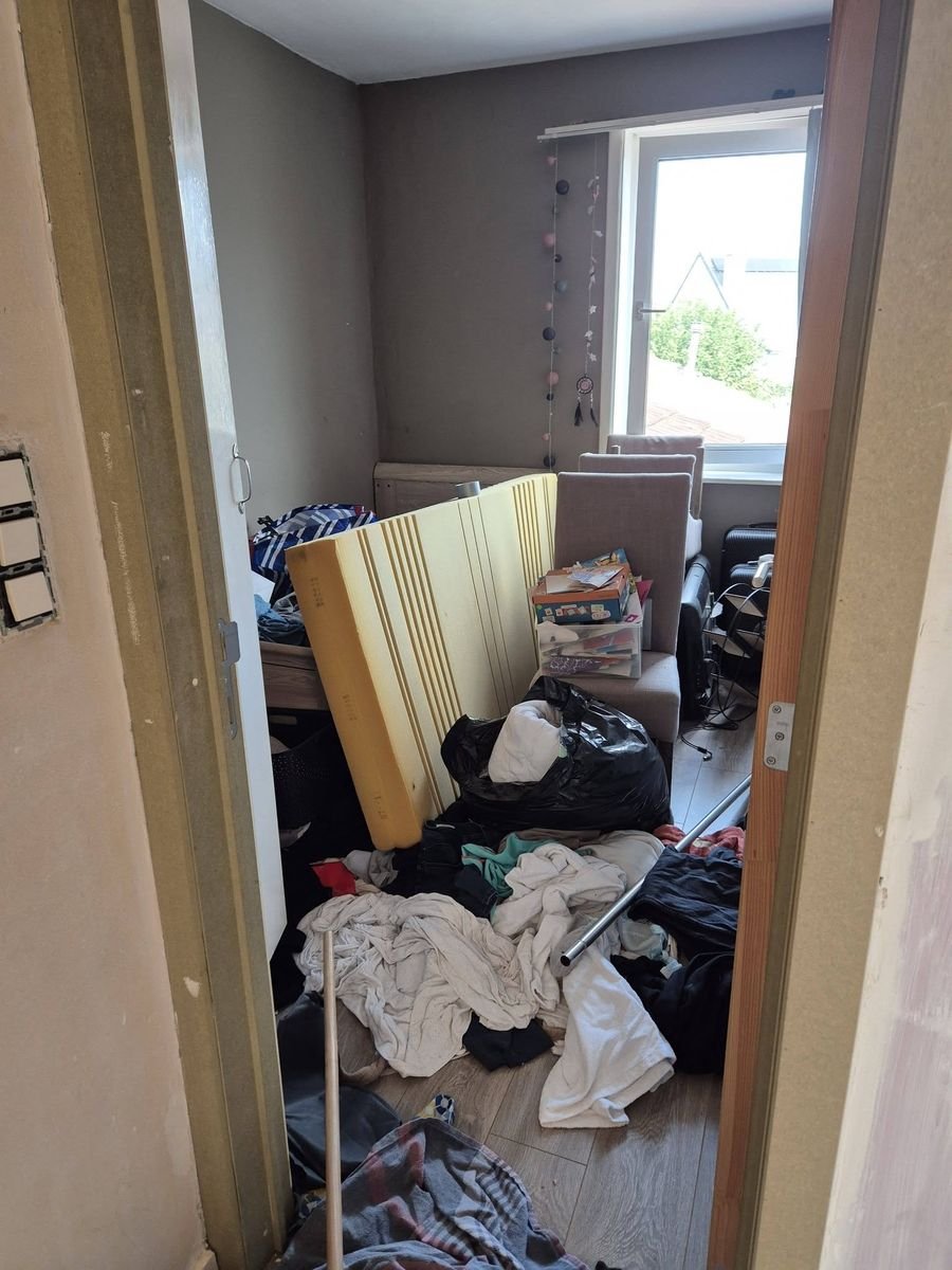 Slaapkamer met kleding, zakken en afval voor de opruiming